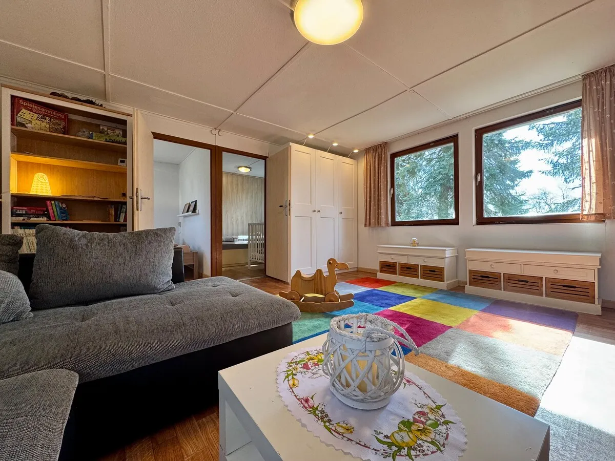 Heller Wohnbereich mit Sofa und Spielteppich